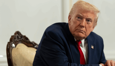 Donald Trump siedzi na krześle, patrząc w bok z poważnym wyrazem twarzy.