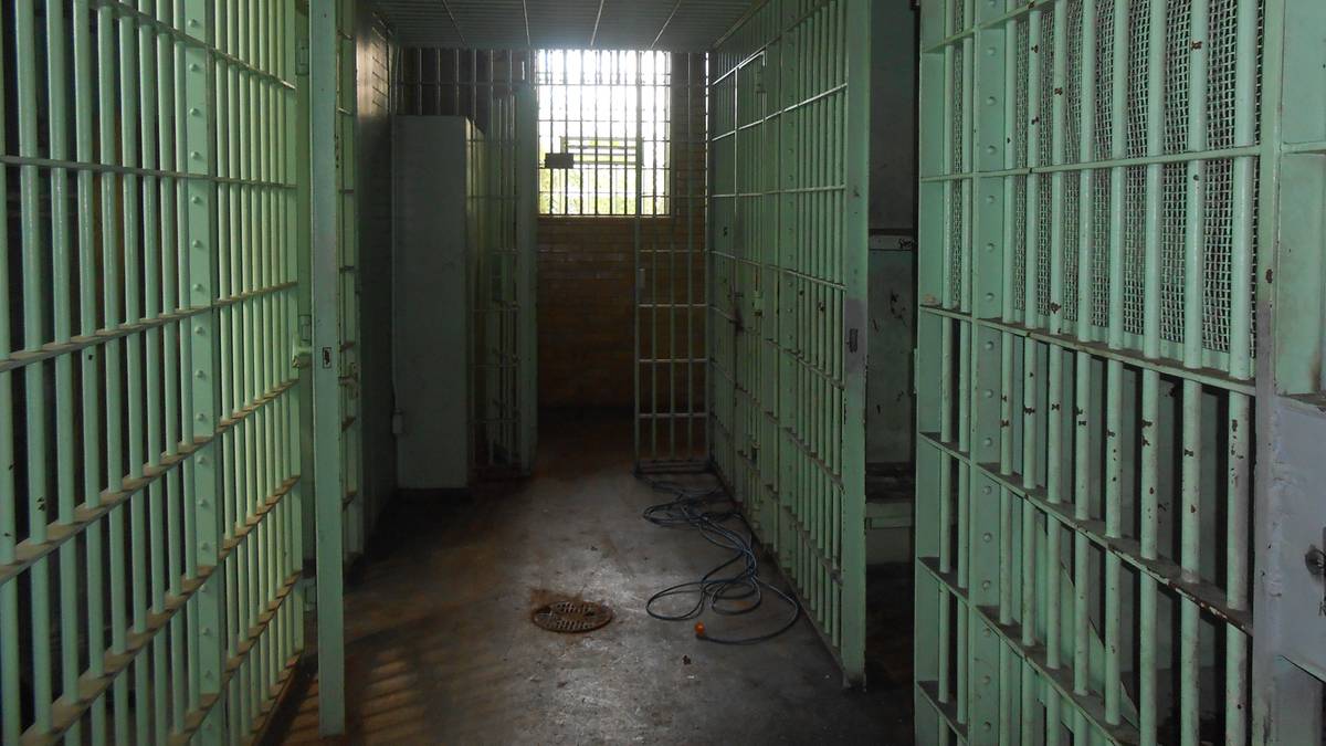 Korytarz więzienny z celami po obu stronach, z oknem na końcu korytarza.