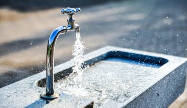 Bieżąca woda z kranu rozpryskująca się nad kamienną umywalką.