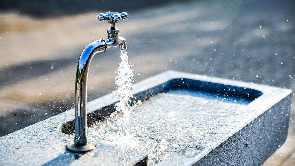 Bieżąca woda z kranu rozpryskująca się nad kamienną umywalką.