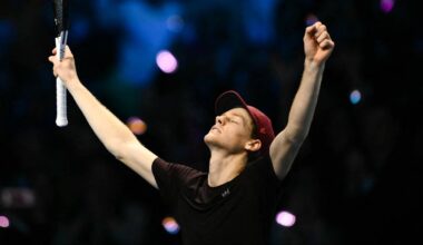 Jannik Sinner unosi rakietę tenisową w geście triumfu, świętując zwycięstwo.