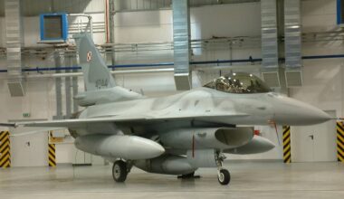 Szary samolot myśliwski F-16 z polskimi oznaczeniami w hangarze