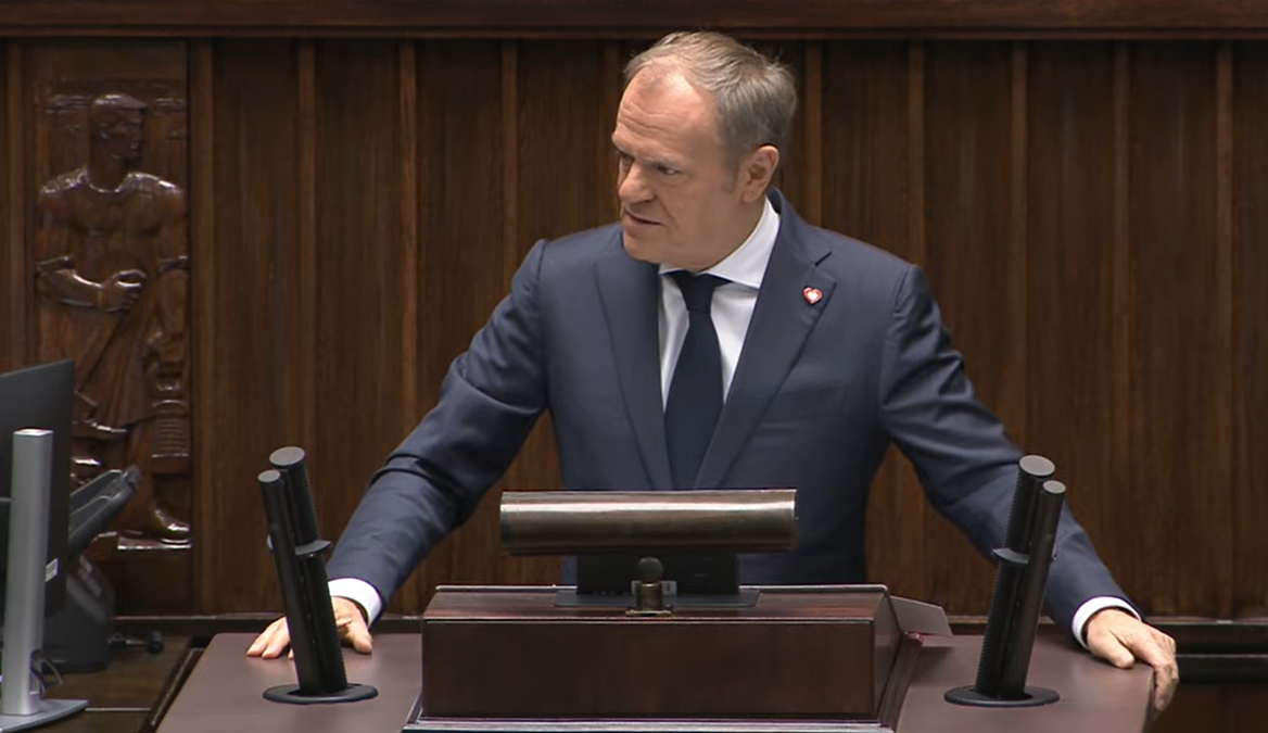 Donald Tusk, premier Polski, przemawia za mównicą w sali sejmowej.