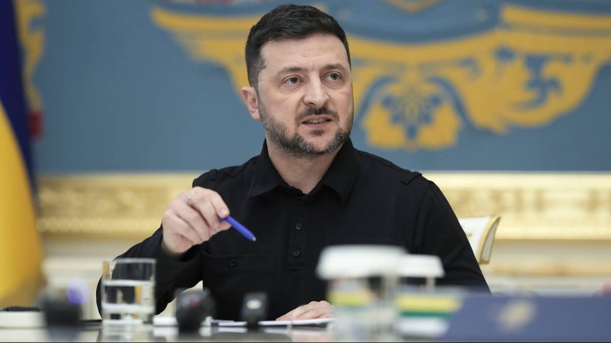 Wołodymyr Zełenski, prezydent Ukrainy, siedzi przy stole i gestykuluje piórem podczas rozmowy lub wywiadu.