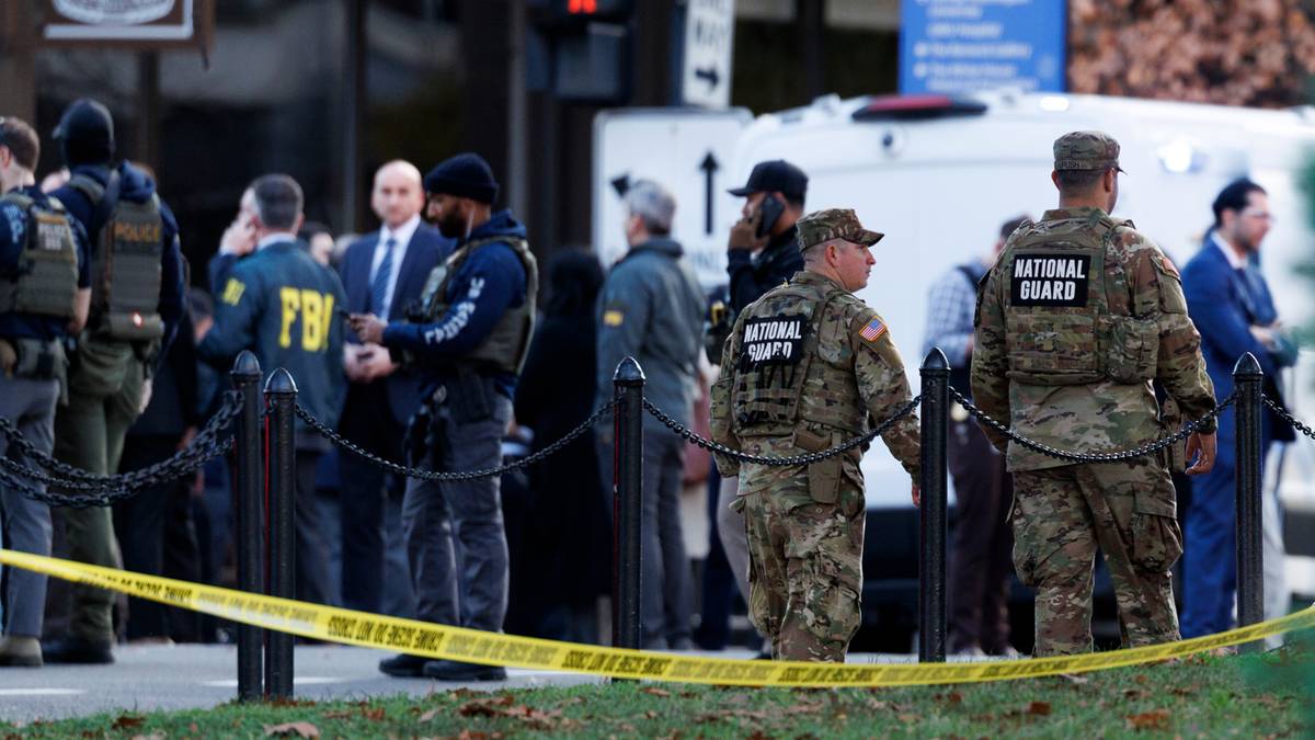 Grupa umundurowanych funkcjonariuszy FBI i Narodowej Gwardii stoi za żółtą taśmą zabezpieczającą.