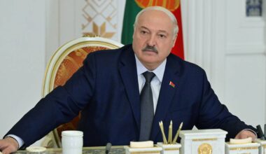 Aleksandr Łukaszenka, prezydent Białorusi, siedzi przy biurku w garniturze.