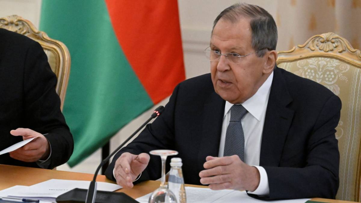 Siergiej Ławrow, minister spraw zagranicznych Rosji, siedzi przy stole podczas konferencji prasowej, przemawiając z gestykulacją. W tle widoczna jest flaga Białorusi.