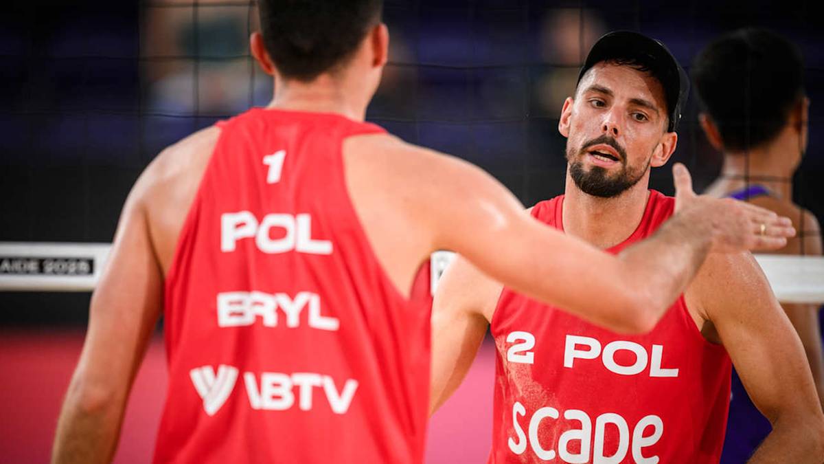 Dwóch polskich siatkarzy plażowych, jeden z numerem 1 i nazwiskiem Bryl, drugi z numerem 2, rozmawiają ze sobą na boisku.