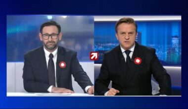 Dwaj mężczyźni w garniturach siedzący przy stołach, prawdopodobnie podczas debaty politycznej.