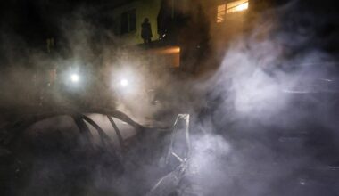 Nocny widok miejsca po ataku dronów w Charkowie, z unoszącym się dymem i światłami pojazdów.