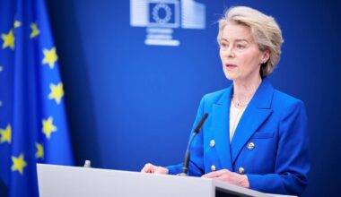 Ursula von der Leyen, przewodnicząca Komisji Europejskiej, przemawia za mównicą na tle flagi Unii Europejskiej.