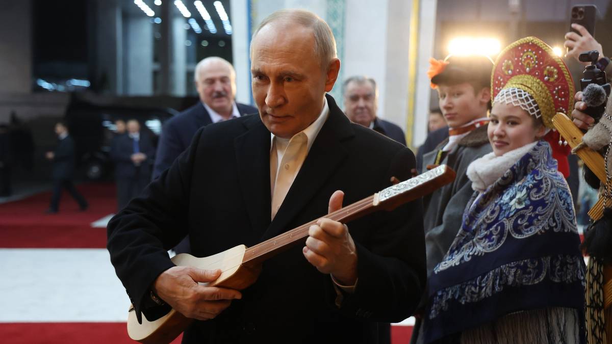 Władimir Putin trzyma w rękach instrument muzyczny.