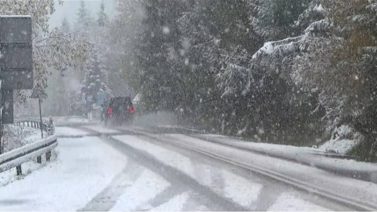 Droga pokryta śniegiem, po której porusza się samochód w trakcie opadów śniegu.