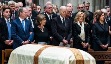 Grupa polityków, w tym Joe Biden, uczestniczy w uroczystości pogrzebowej Dicka Cheneya, stojąc obok przykrytej trumny.