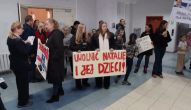 Grupa osób, w tym dzieci, trzyma transparenty z hasłami poparcia dla Natalii i jej dzieci, którzy zostali zatrzymani w Niemczech.