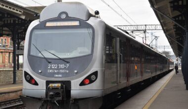 Srebrno-szary pociąg z numerem 2122 310-7 stoi na peronie dworca kolejowego.