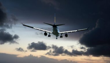 Widok od tyłu na samolot pasażerski w locie, na tle ciemnych, burzowych chmur o zachodzie słońca.