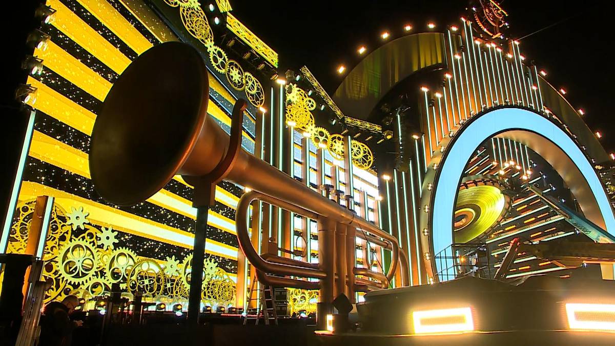 Złota trąbka na tle oświetlonej sceny sylwestrowej.