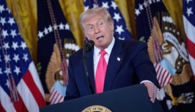 Donald Trump przemawia za mównicą na tle amerykańskich flag.