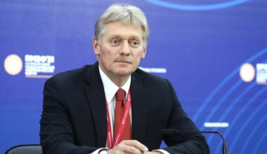 Mężczyzna w garniturze i krawacie siedzi przy stole.