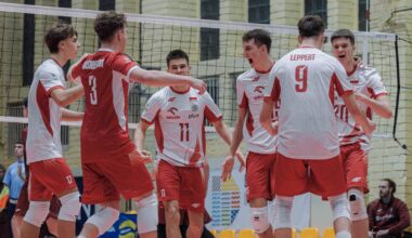 Drużyna siatkarzy w czerwono-białych strojach świętuje na boisku.