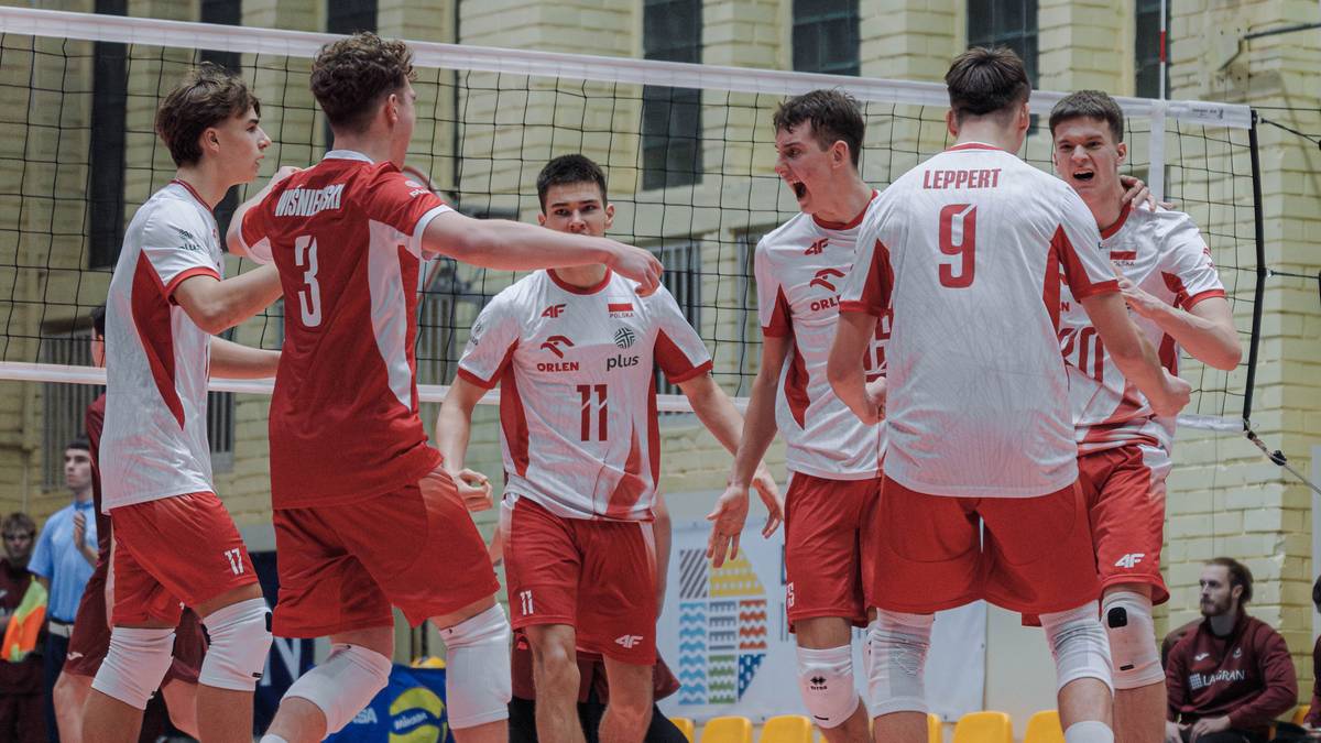 Drużyna siatkarzy w czerwono-białych strojach świętuje na boisku.