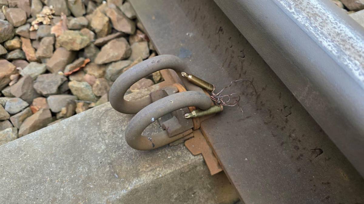 Fragment torów kolejowych z elementami mocującymi szyny, na jednym z elementów znajduje się zardzewiały przedmiot.