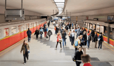 Stacja metra z pociągami i podróżnymi na peronie.