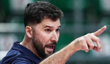 Mężczyzna w granatowej koszulce wskazuje palcem na coś poza kadrem.