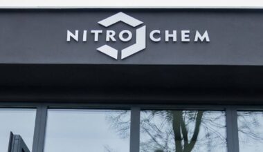 Napis NITRO CHEM z logo nad przeszklonym wejściem do budynku.