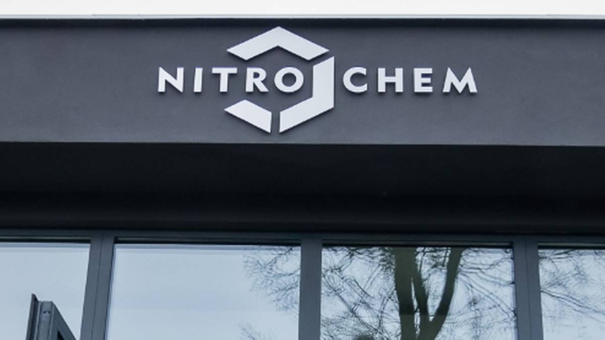 Napis NITRO CHEM z logo nad przeszklonym wejściem do budynku.