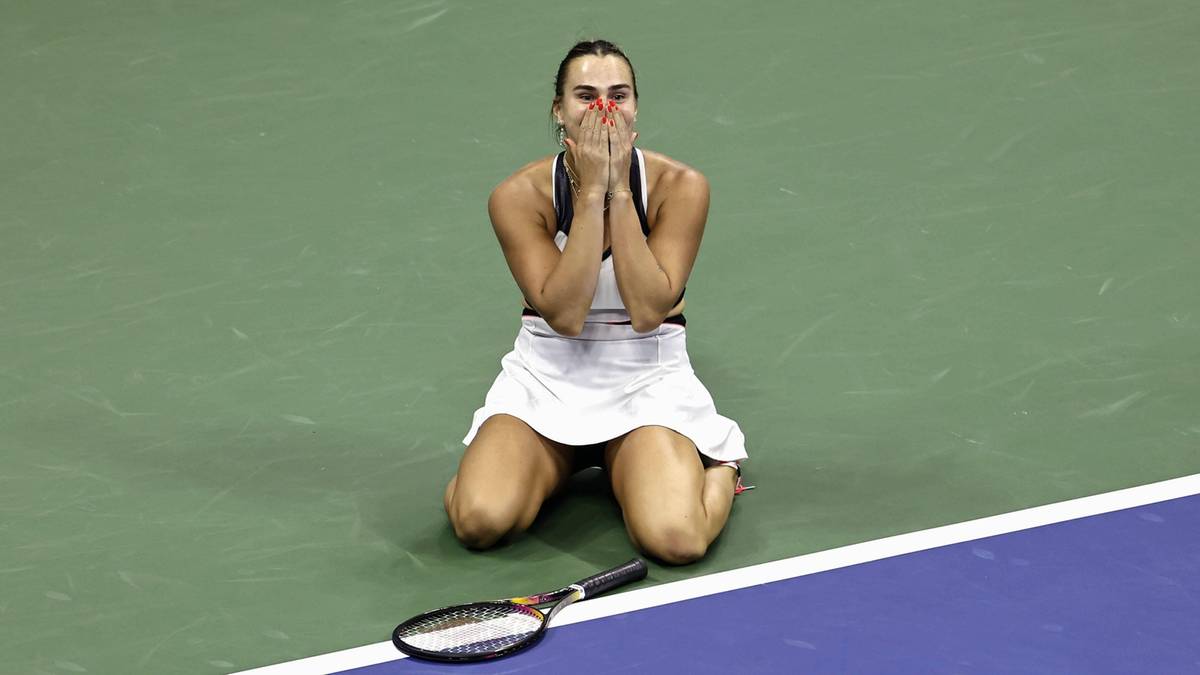 Białoruska tenisistka Aryna Sabalenka klęczy na korcie z rękami przy twarzy, z radością lub ulgą po zwycięstwie w meczu.