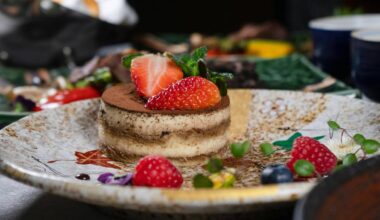 Tiramisu ozdobione świeżymi owocami, w tym truskawkami i malinami, na eleganckim talerzu.