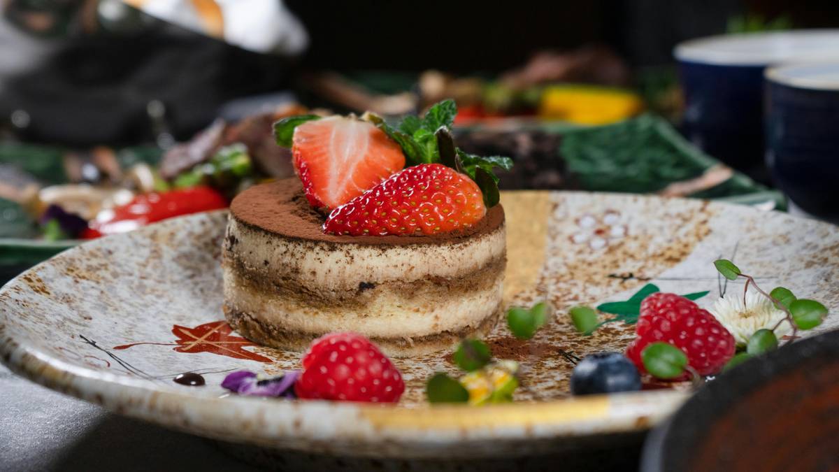 Tiramisu ozdobione świeżymi owocami, w tym truskawkami i malinami, na eleganckim talerzu.