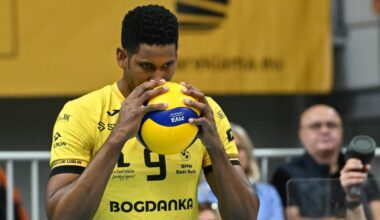 Siatkarz w żółtej koszulce Bogdanki LUK Lublin trzyma piłkę siatkową.