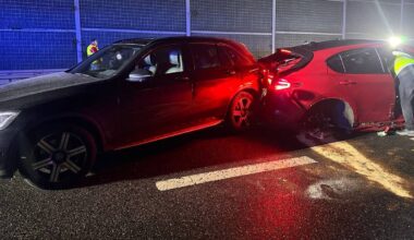 Widok na nocny karambol na trasie S2. Dwa samochody osobowe, jeden czerwony i jeden ciemny, stoją na drodze, z widocznymi uszkodzeniami. W tle znajdują się bariery dźwiękochłonne i światła pojazdów ratowniczych.