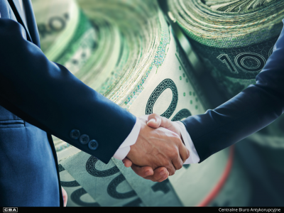 Uścisk dłoni, w tle banknoty polskie.