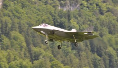 Nowoczesny myśliwiec F-35A podczas lotu na tle zalesionego wzg&oacute;rza.