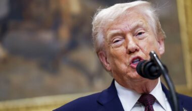 Donald Trump przemawia do mikrofonu, ubrany w granatowy garnitur i krawat.