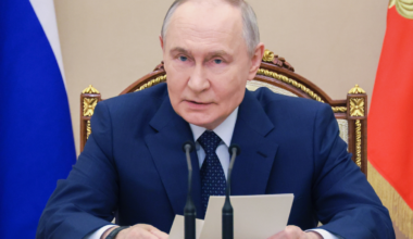 Władimir Putin, prezydent Rosji, siedzi przy stole i przemawia.