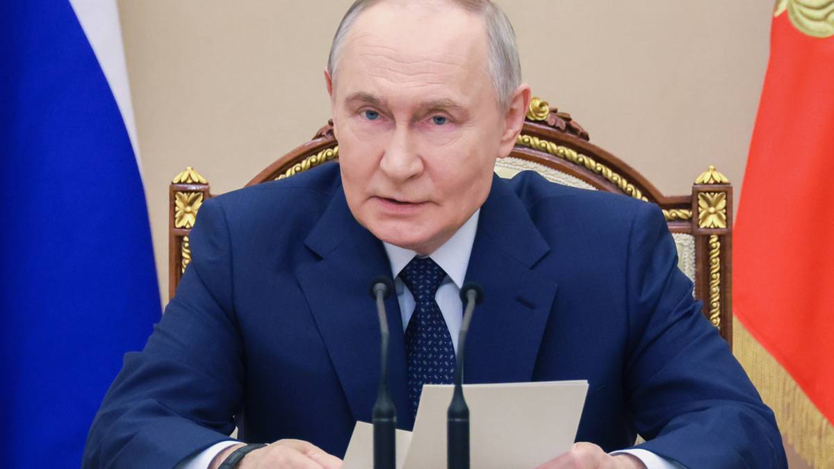 Władimir Putin, prezydent Rosji, siedzi przy stole i przemawia.