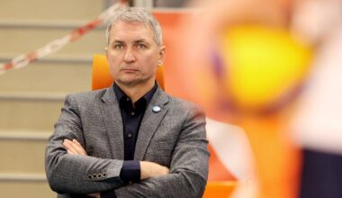 Mężczyzna w garniturze siedzi ze skrzyżowanymi rękami, patrząc przed siebie.