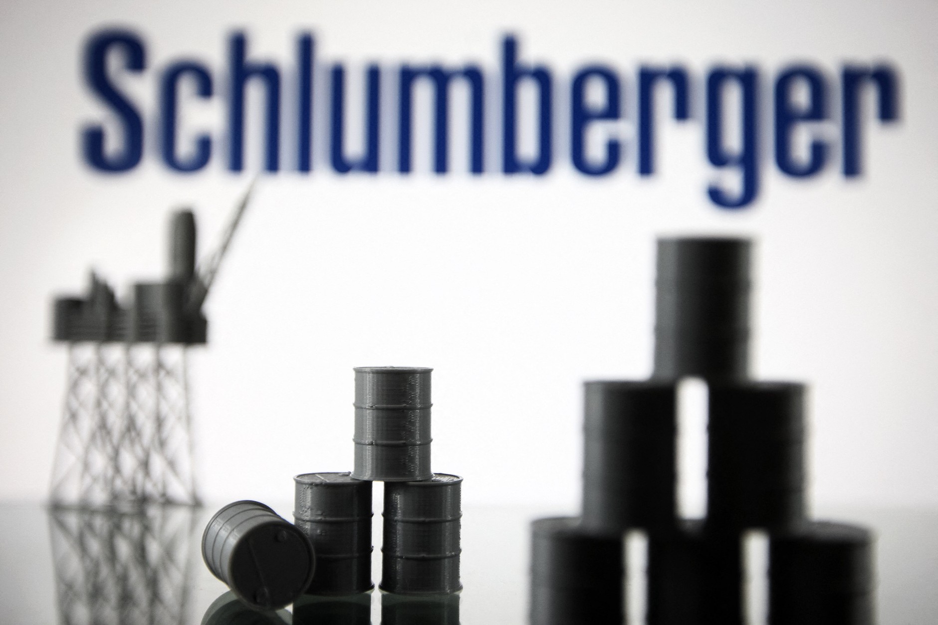 Logo Schlumberger Limited (obecnie SLB) oraz modele platformy wiertniczej i beczek z ropą naftową, Kijów, Ukraina, 19 sierpnia 2021 r.