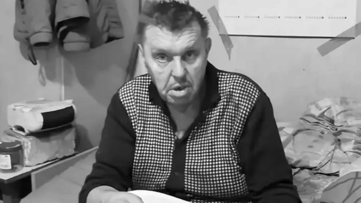 Krzysztof Kononowicz siedzi w pomieszczeniu, patrząc w obiektyw. Ma na sobie koszulę w kratę.