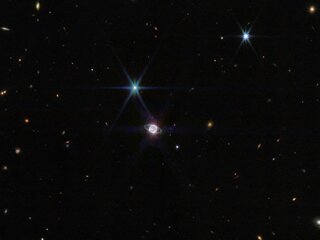 Zdjęcie wykonane przez Kosmiczny Teleskop Jamesa Webba (w bliskiej podczerwieni - NIRCam) w szerokim polu widzenia, pośrodku układ Neptuna z widocznymi pierścieniami