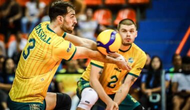 Dw&oacute;ch siatkarzy w ż&oacute;łtych koszulkach z numerami 3 i 2, jeden z nich podaje piłkę.