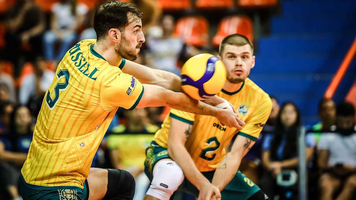 Dw&oacute;ch siatkarzy w ż&oacute;łtych koszulkach z numerami 3 i 2, jeden z nich podaje piłkę.