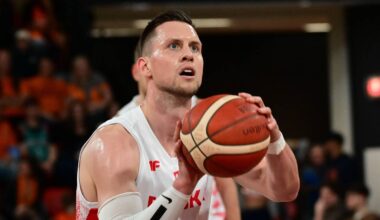 Koszykarz z numerem 9 na koszulce, trzymający piłkę do koszykówki przed rzutem.