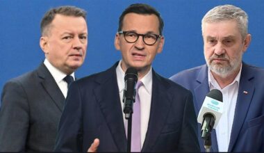 Trzech mężczyzn w garniturach, z których jeden przemawia do mikrofonu.