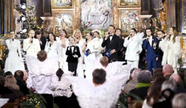 Artyści występują na scenie w kościele podczas koncertu kolęd, w tłumie widz&oacute;w.